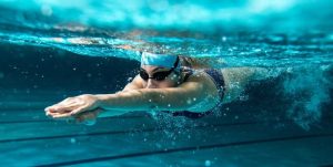 a woman is swimming under water. Swimming triggers acid reflux